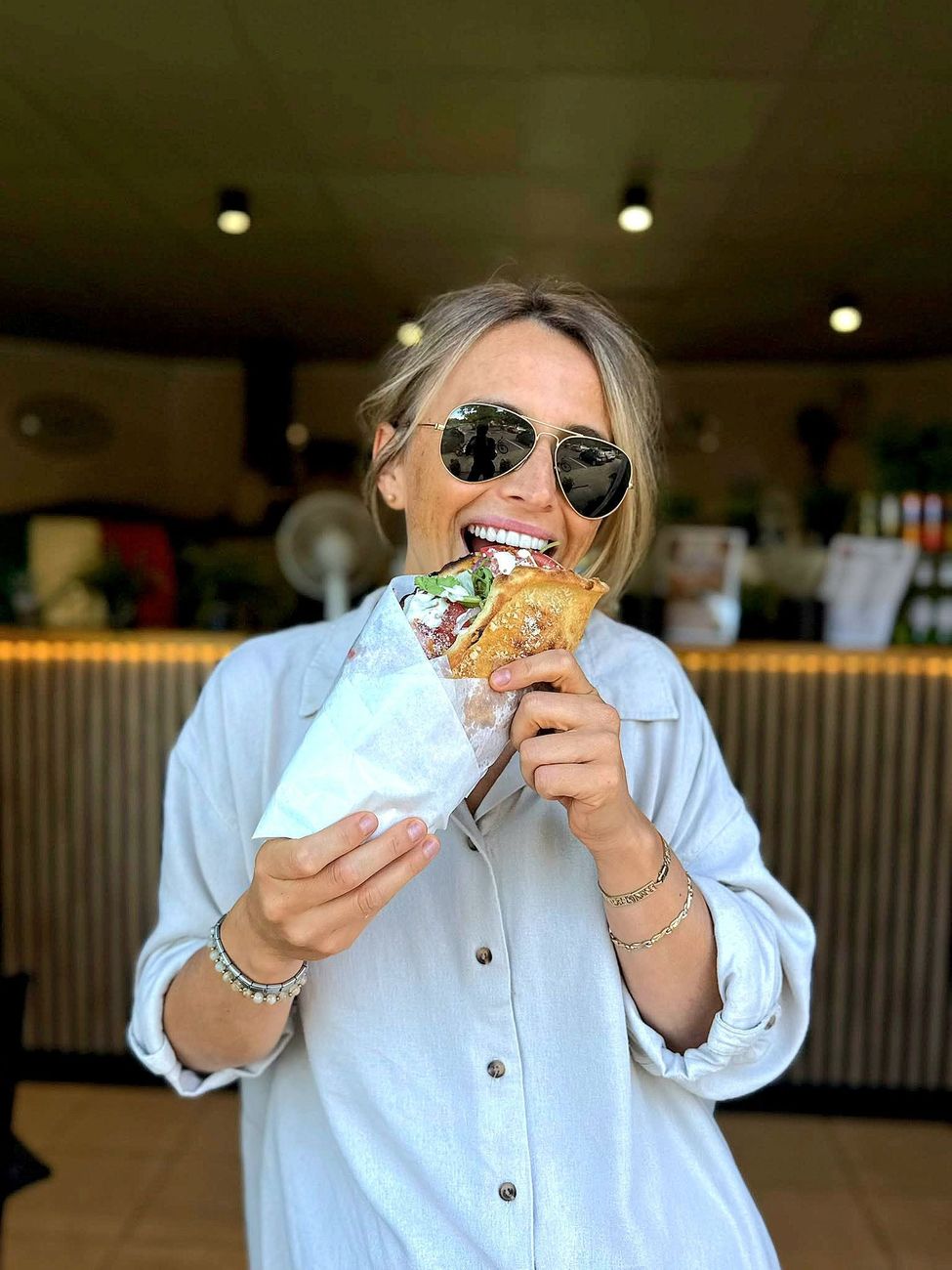 Uśmiechnięta klientka wgryza się w panuozzo przed ladą pizzerii
